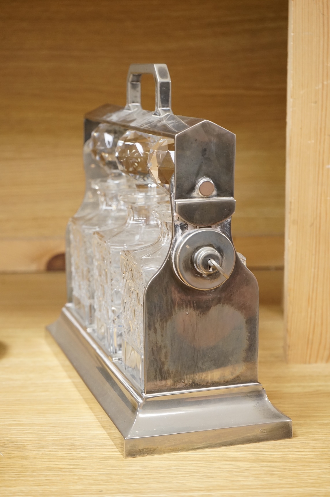 A silver plated three bottle tantalus, 34cm wide.